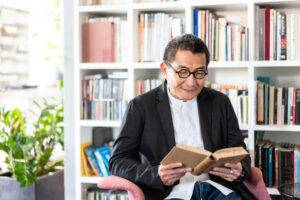 senior reading book in small personal library