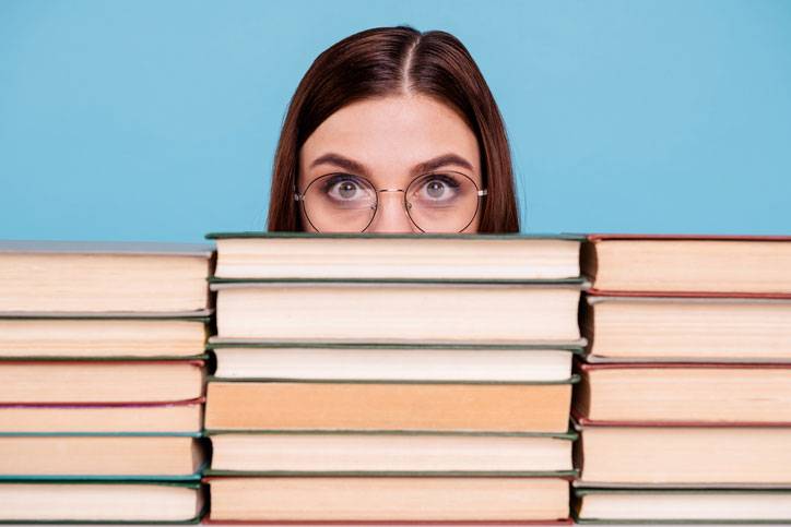 young woman behind a stack of books
