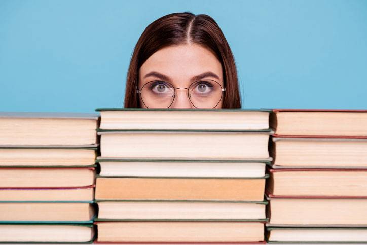 young woman behind a stack of books