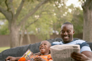 father and son laughing while reading