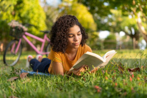 teen reading outside in grass