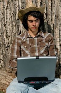 young cowboy writing on a laptop