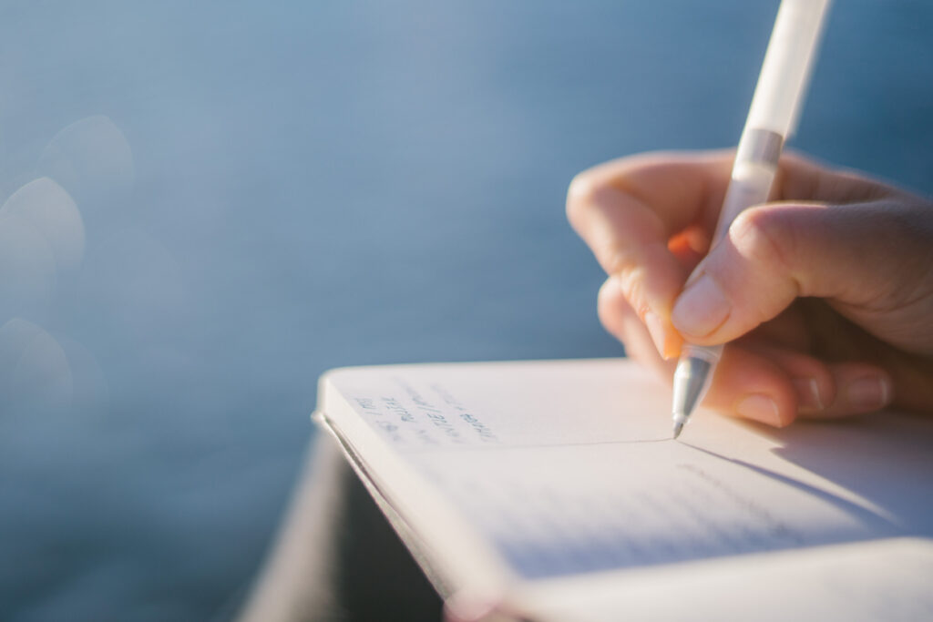 Woman writing in her journal while practicing creative writing.